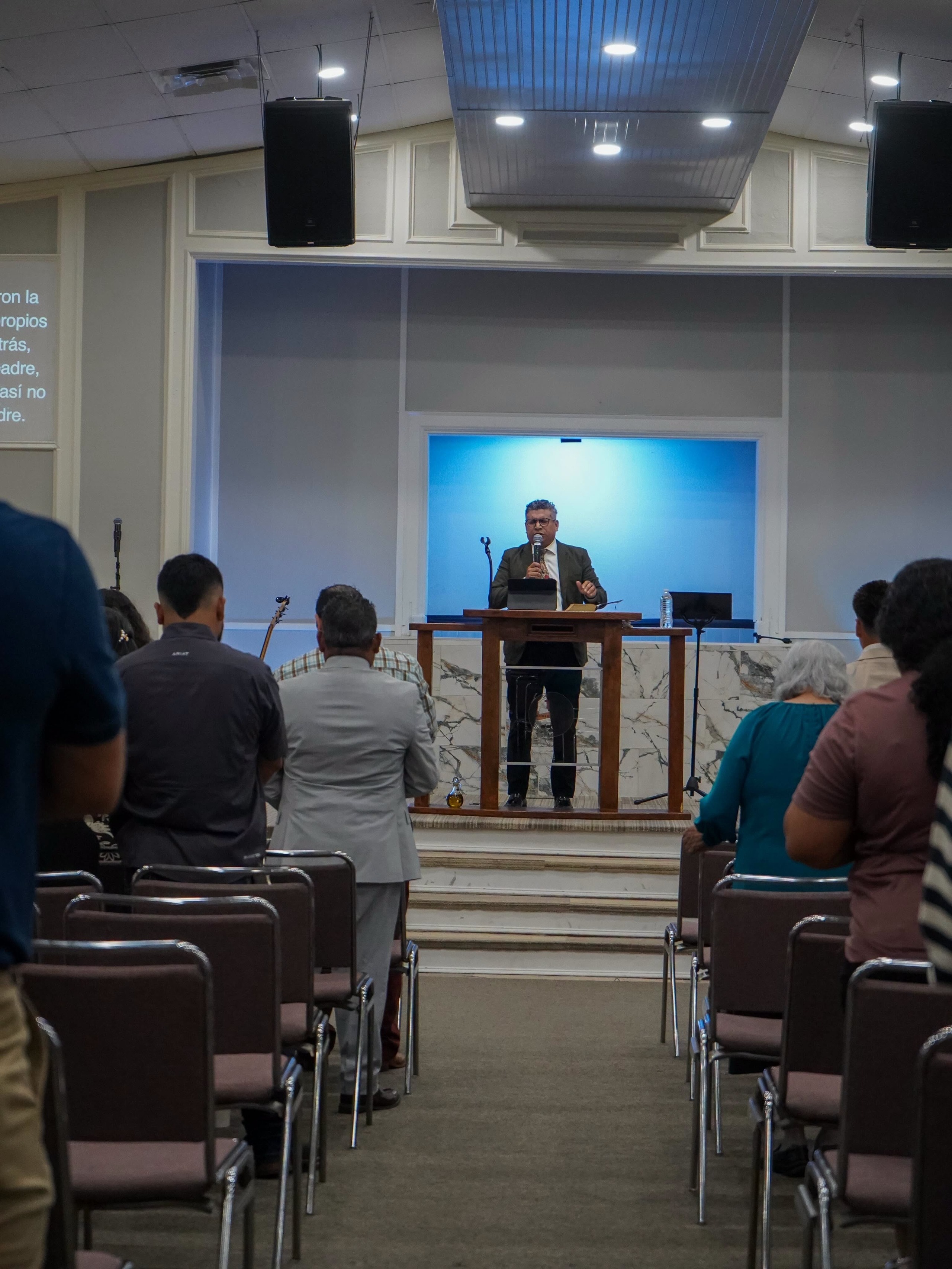 El pastor predicando desde el púlpito a la congregación, visto desde el fondo del salón