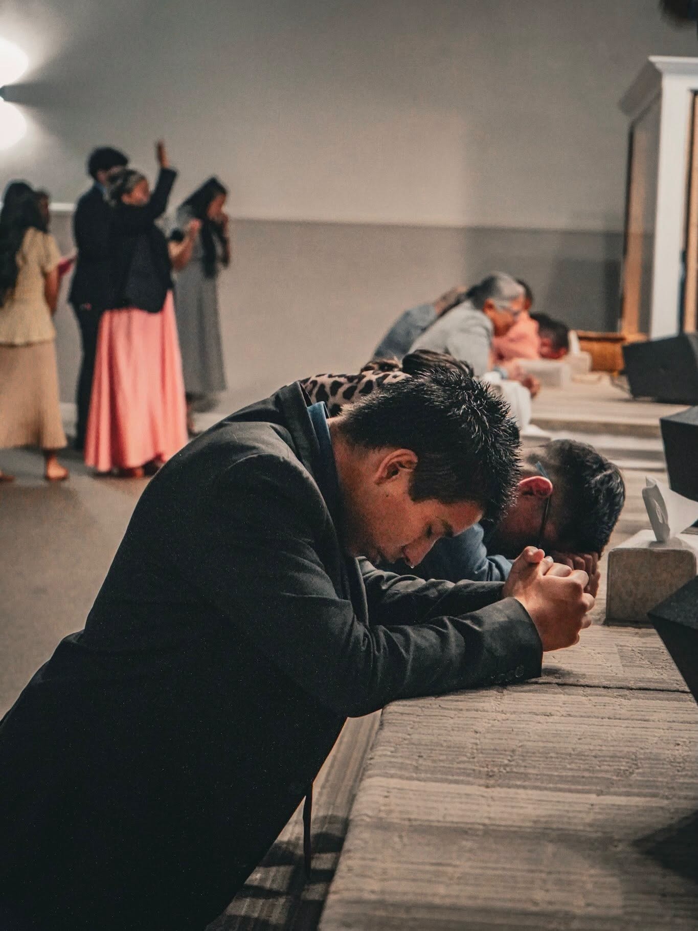 Jóvenes arrodillados en oración en el altar durante un culto de jóvenes